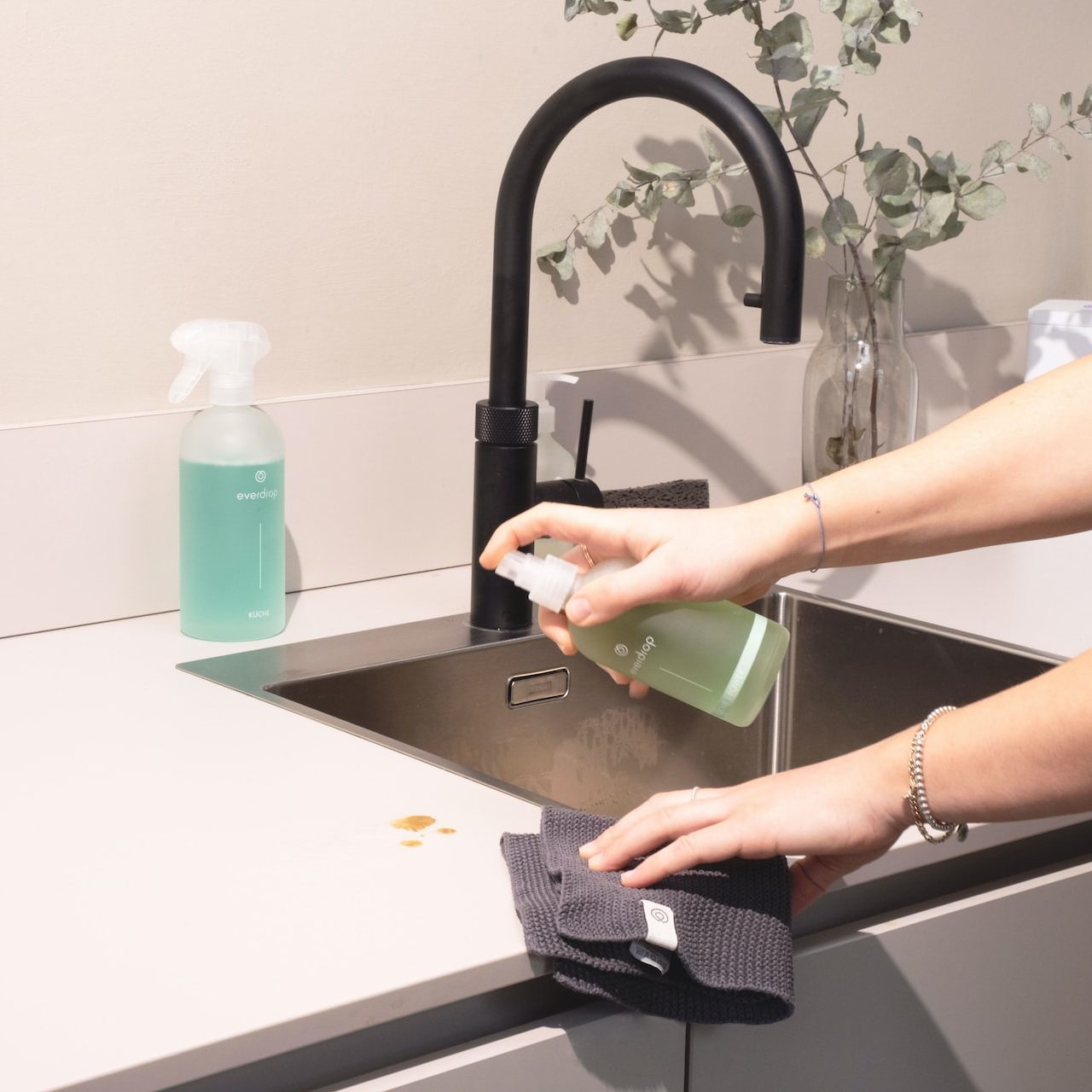 a woman is cleaning a kitchen sink with a rag